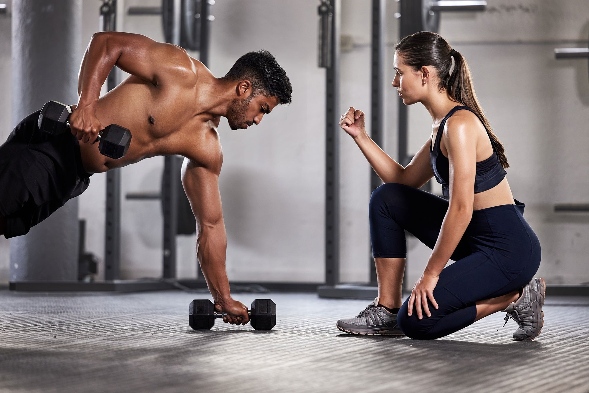 Coach and member training with dumbbells under warm studio lighting